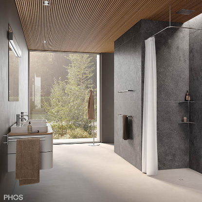 PHOS Design Badezimmer mit einer Duschvorhangstange in L-Form, Handtuchhaltern und einer Standgarderobe aus Edelstahl.